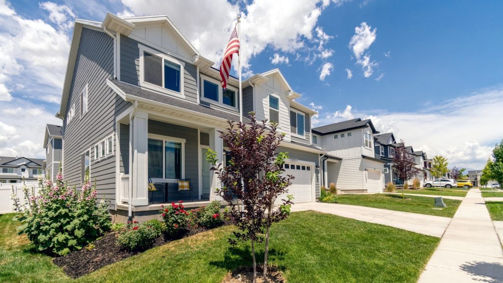 Modern two-story suburban homes with an American flag beneath a blue sky.